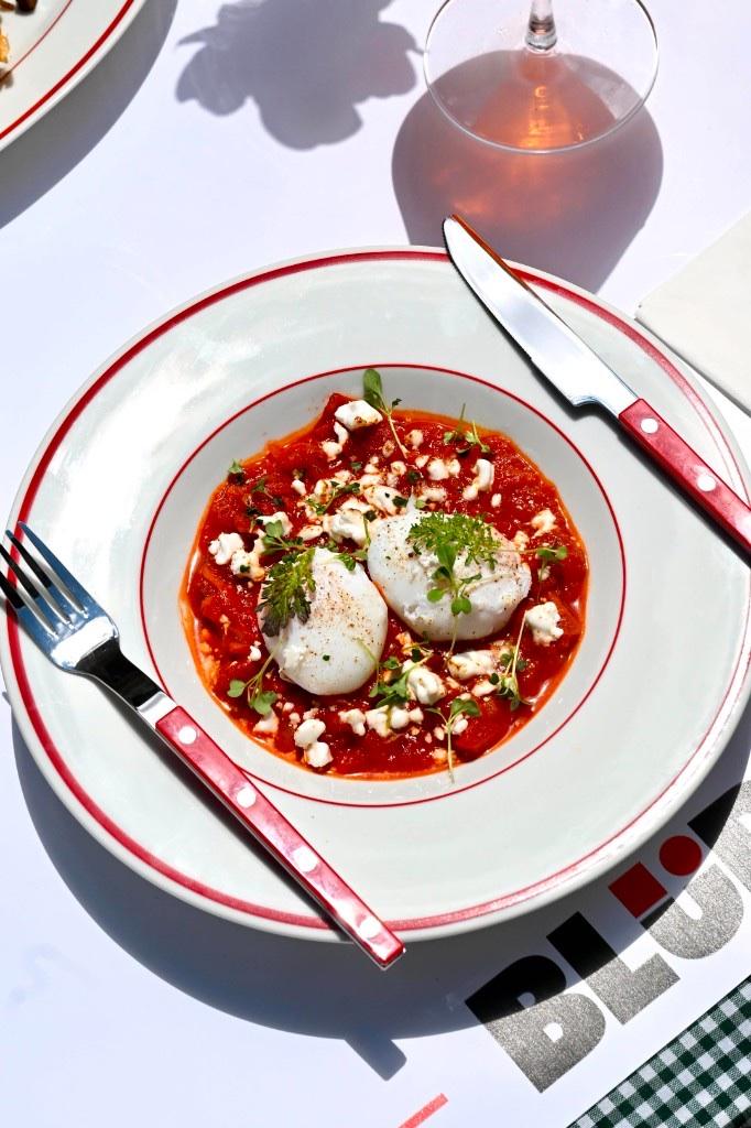 Shakshuka pe farfurie cu margine roșie, tacâmuri BLÜR